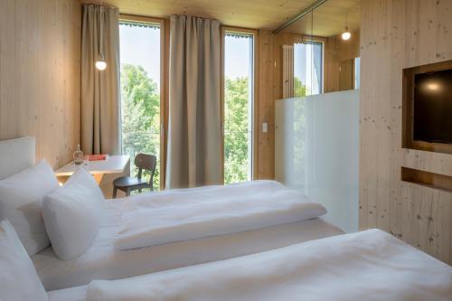 a hotel room with two beds and a desk and a window at Bader Hotel in Parsdorf