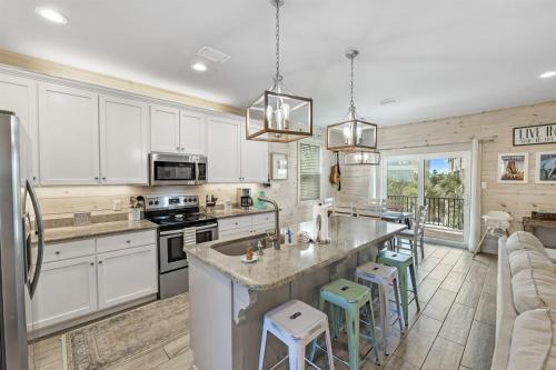 a kitchen with white cabinets and a kitchen island with stools at PRIME Coral Dreams Walk to Beach Pool Pets Near The Hangout Parking in Gulf Shores