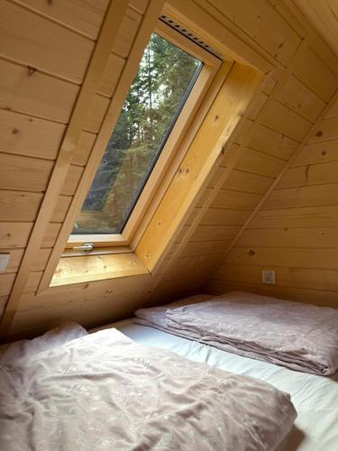 a bed in a wooden room with a window at Tiny house nad potokiem in Sidzina