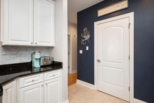 a kitchen with white cabinets and a white door at Salty Girl by Oak Island Accommodations in Oak Island