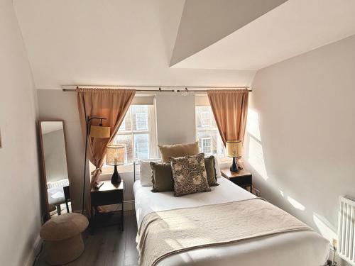 a bedroom with a bed with pillows and two windows at Soho Room n4 in London