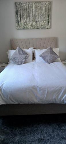 a bed with white sheets and pillows in a bedroom at Highwood mews in Cleethorpes