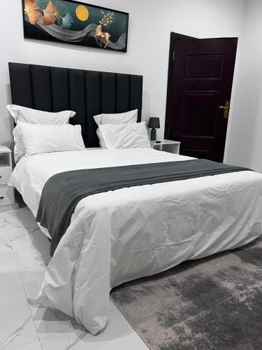a large bed with a black headboard and white sheets at Muka Staytel in Ndola
