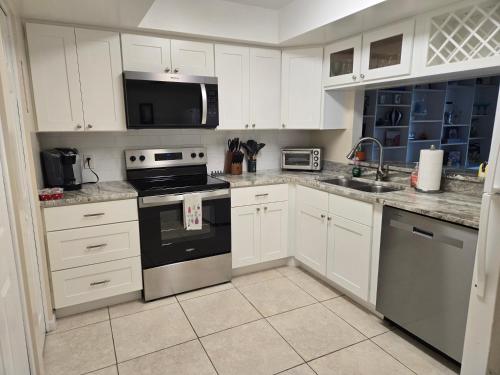 a kitchen with white cabinets and stainless steel appliances at Your Space Coast Home - 30 Seconds to Sand in Cape Canaveral