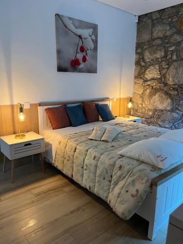 a bedroom with a bed and a stone wall at Casa De Cantoneiros in Campos