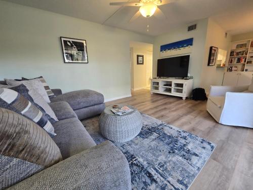 a living room with a couch and a flat screen tv at Your Space Coast Home - 30 Seconds to Sand in Cape Canaveral