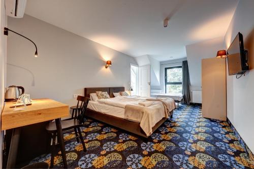 a bedroom with a bed and a table and a desk at Początek Jutra in Pajewo