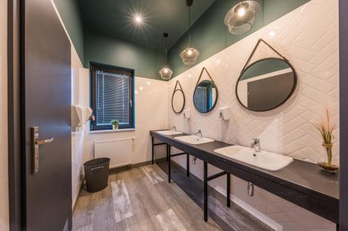 a bathroom with two sinks and two mirrors at Początek Jutra in Pajewo
