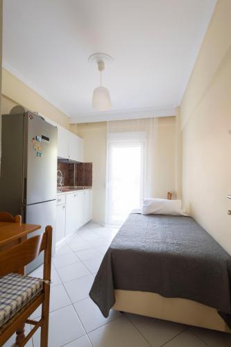 a bedroom with a bed and a refrigerator and a window at Nearby the sea in Asprovalta