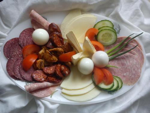 a plate of food with meat cheese and vegetables at Alabástrom Panzió és Étterem in Bogács