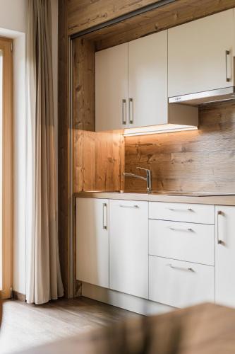 a kitchen with white cabinets and a sink at Chalet Schaller in Missiano