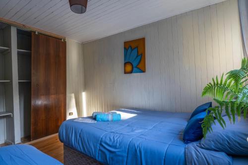 a bedroom with a blue bed with a painting on the wall at Hostal refugio nomada in Puerto Montt