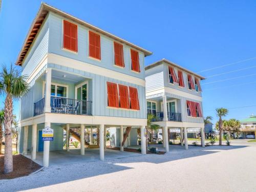 a two story building with red windows and palm trees at PRIME True Blue Walk to Beach Pool Pets Near The Hangout Parking in Gulf Shores