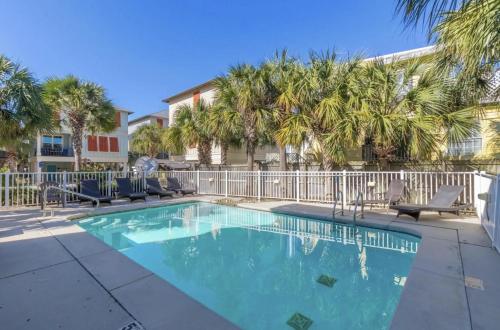 a swimming pool with chairs and palm trees at PRIME True Blue Walk to Beach Pool Pets Near The Hangout Parking in Gulf Shores