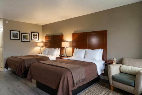 a hotel room with two beds and a chair at Rodeway Inn Monroe in Monroe