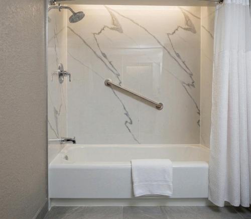 a bathroom with a white bath tub with a shower curtain at Rodeway Inn Monroe in Monroe