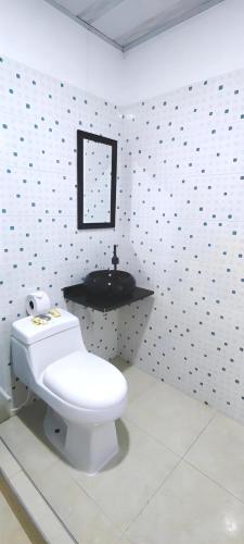 ein Badezimmer mit weißer Toilette und Waschbecken in der Unterkunft Hotel San Rin in Nilo