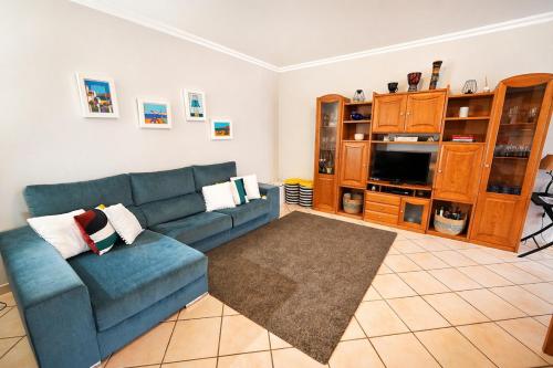 a living room with a blue couch and a tv at Nova Onda - Cozy 2BR Apartment with Private Terrace in Nazaré