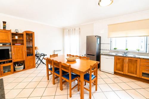 a kitchen with a wooden table and a refrigerator at Nova Onda - Cozy 2BR Apartment with Private Terrace in Nazaré