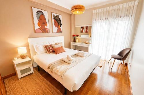 a bedroom with a large white bed and a chair at Nova Onda - Cozy 2BR Apartment with Private Terrace in Nazaré