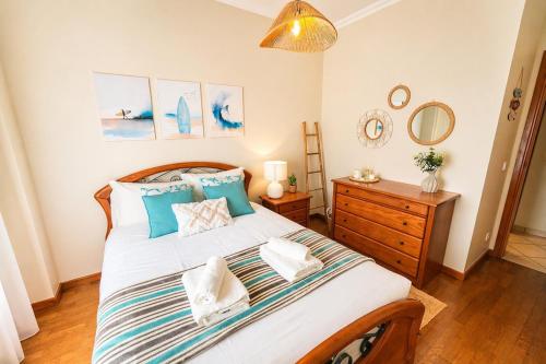 a bedroom with a large bed with blue pillows at Nova Onda - Cozy 2BR Apartment with Private Terrace in Nazaré