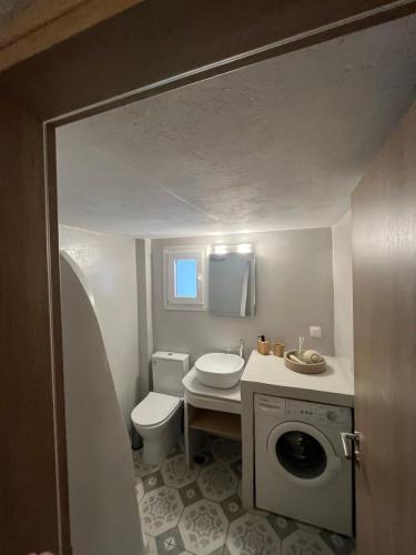 a bathroom with a toilet and a washing machine at AJ studios by the Sea in Kithnos