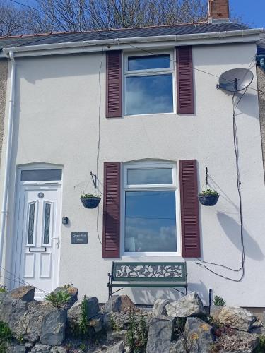 a white house with a bench in front of it at Copper Mine Cottage in Llandudno