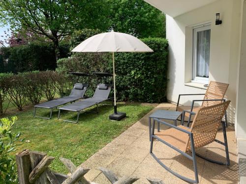 a group of chairs and an umbrella on a patio at Appartement spacieux au calme in Vannes
