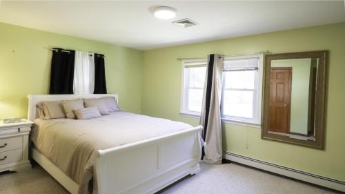 a bedroom with a white bed and a mirror at Centrally Located, Outdoor Dinning and Game Table in Barnstable