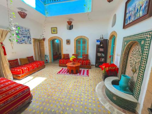 a living room with red couches and a table at Dar darkom in Essaouira