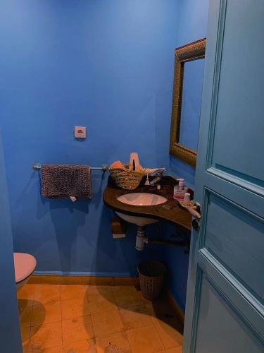 a blue bathroom with a sink and a mirror at Dar darkom in Essaouira