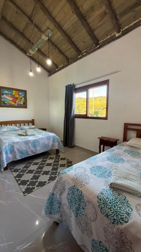 a bedroom with two beds and a window at Pousada Recanto Namastê - Mandalah in Cunha