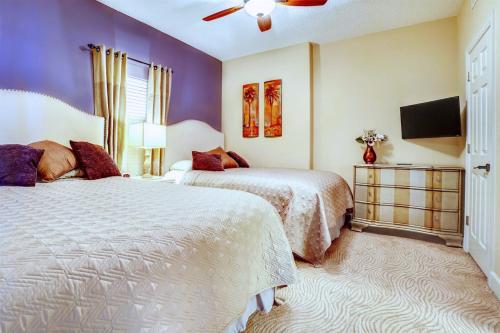a bedroom with two beds and a flat screen tv at Luxury Beachfront Condo Free Beach Chairs Huge Balcony Come Relax! in Panama City Beach