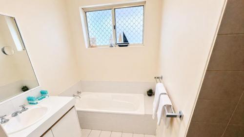a bathroom with a tub and a sink and a window at The Orchid Courthouse - Busselton in Geographe