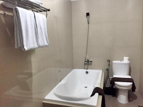 a bathroom with a tub and a toilet and towels at Avilla Puncak in Puncak