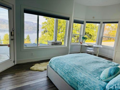 a bedroom with large windows and a bed and a desk at Lakeview Bed and Breakfast in Kelowna