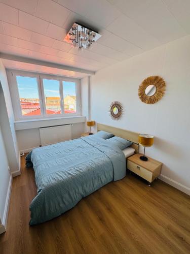 a bedroom with a blue bed and a window at La Maison du Chenal in Gravelines