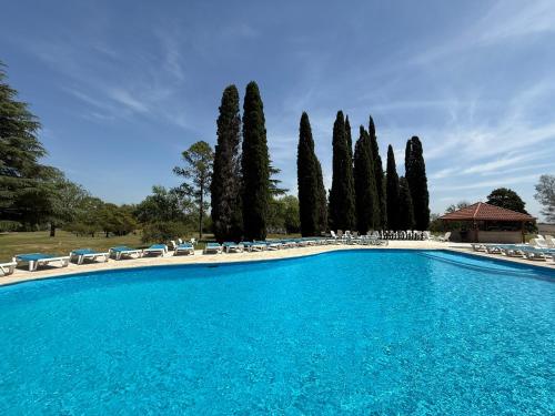 a large swimming pool with chairs and trees at San Miguel Plaza Hotel All Inclusive in Villa San Miguel