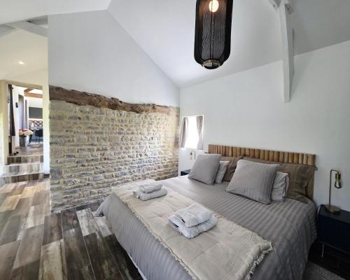 a bedroom with a bed and a brick wall at Gite Les Petits Monts in Commes