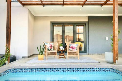 two chairs and a table next to a pool at Cape Winelands Mountain View Getaway in Dalsig