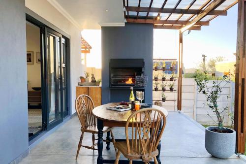 a patio with a table and chairs and a fireplace at Cape Winelands Mountain View Getaway in Dalsig