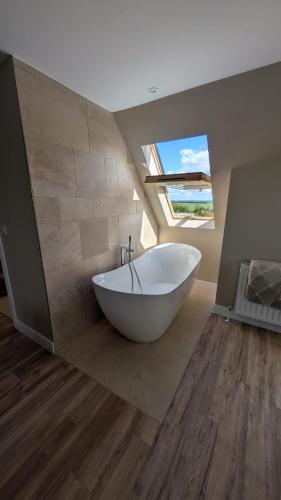 a large white tub in a bathroom with a window at The Wimpey At Mill Cottage in Bedford