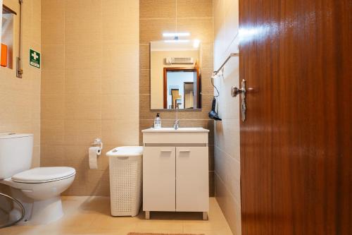 a bathroom with a toilet and a sink and a mirror at Almeida's House in Figueira da Foz