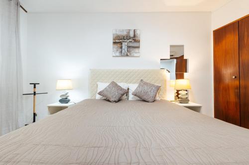 a white bedroom with a large bed with two lamps at Almeida's House in Figueira da Foz