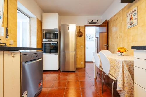 a kitchen with a table and a refrigerator at Almeida's House in Figueira da Foz
