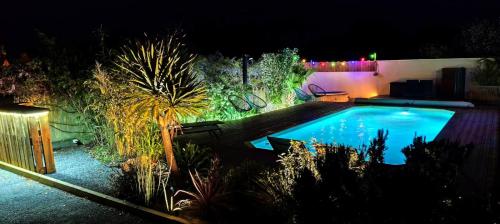a swimming pool in a yard at night at Île Dumet - Appt T2 cocooning - 2 à 4 pers. - Piscine & Spa in La Turballe