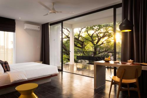 Schlafzimmer mit einem Bett und einem Schreibtisch mit einem Tisch in der Unterkunft Hillocks Hotel & Spa in Siem Reap