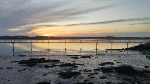 a pier on the water with the sunset in the background at Esposende Garden in Esposende