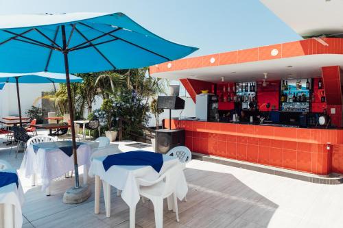 a restaurant with a bar with white tables and blue umbrellas at Hotel el Silencio in Bombiso