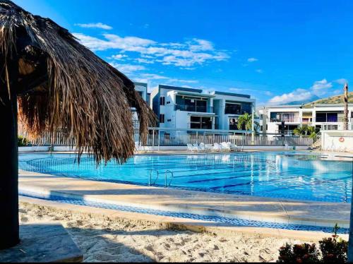 a swimming pool with a straw umbrella and a building at Alojamiento Santa Fe de Antioquia in Santa Fe de Antioquia